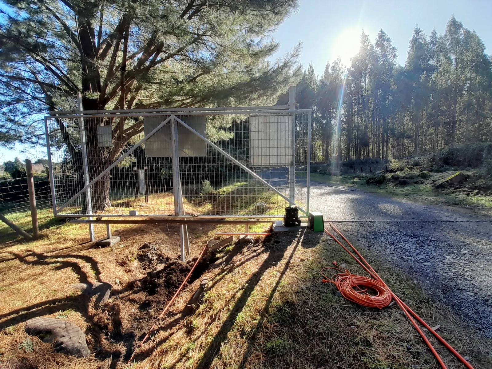 Instalación de un poste con equipos junto a un camino rural rodeado de bosque