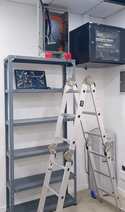Sala técnica con gabinete de red, rack mural y escalera durante una instalación